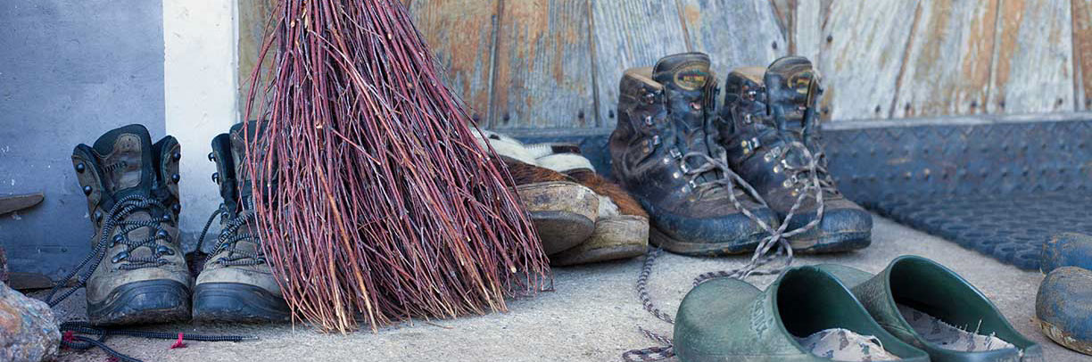 Schuhe und Besen vor einem Bauernhaus